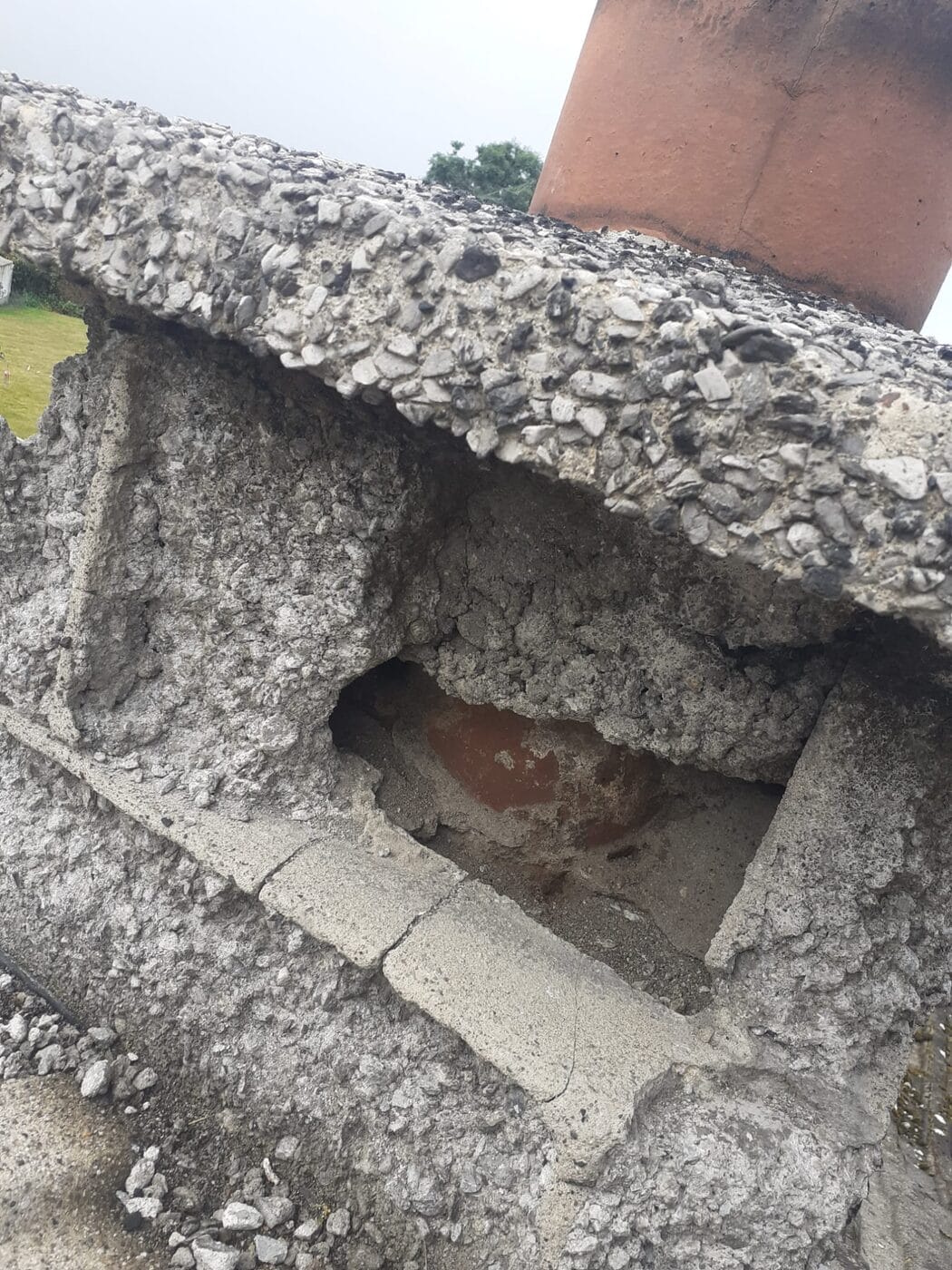 Crumbling concrete capping on top of a chimney stack with the liner exposed