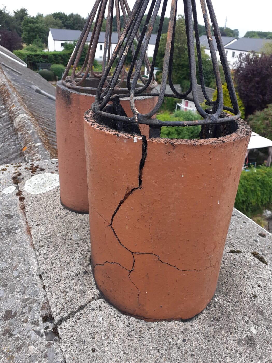 Clay chimney pot with a long vertical crack running down it