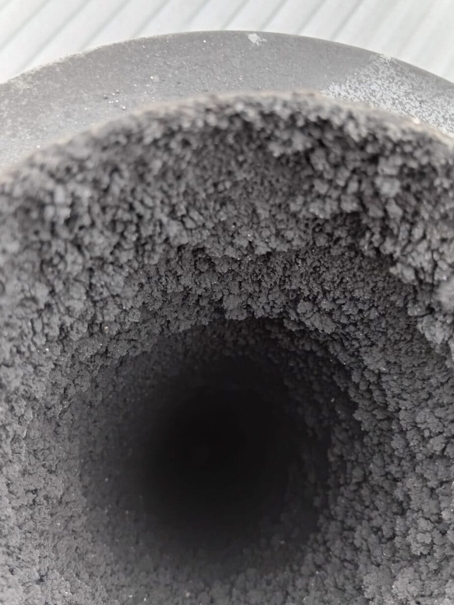 Chimney flue liner packed with a thick layer of soot before sweeping