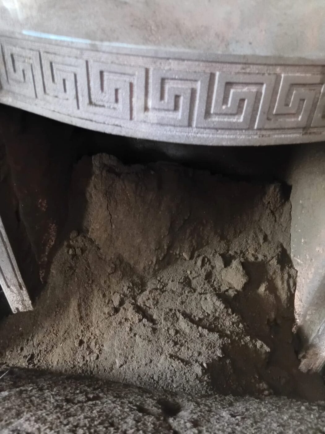 Deep pile of soot behind a cast iron fireplace insert